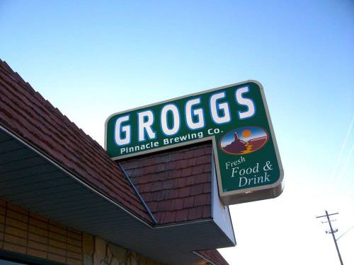 Sign for Groggs Pinnacle Brewing Co. featuring "Fresh Food & Drink" against a clear blue sky.