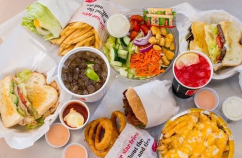 A spread of burgers, fries, onion rings, salads, and drinks on a table, showcasing a variety of fast food items.