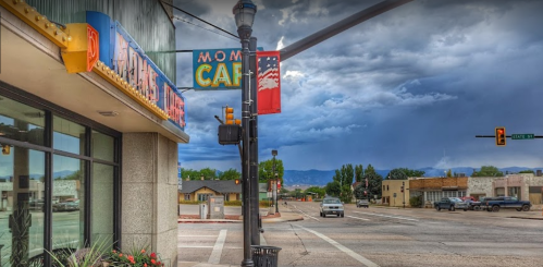 A street view featuring a café sign, traffic light, and cloudy sky with mountains in the background.
