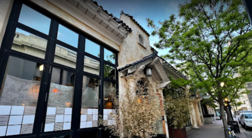 A charming restaurant exterior with large windows, greenery, and a unique architectural design.