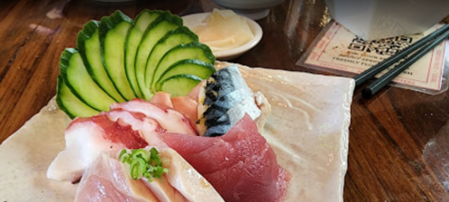 A beautifully arranged plate of sushi featuring various sashimi, garnished with cucumber slices and pickled ginger.