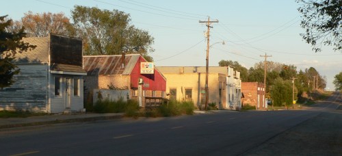 A quiet, small-town street lined with old buildings and a clear sky, evoking a sense of nostalgia.