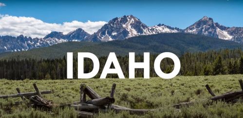 A scenic view of mountains and forest in Idaho, with the word "IDAHO" prominently displayed in white.