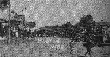 Historic black-and-white photo of a street scene in Burton, Nebraska, with people and early automobiles.