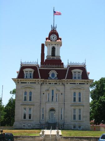 Historic building with a clock tower, red roof, and American flag, set against a clear blue sky.