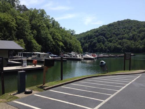 A serene marina with boats docked, surrounded by lush green hills under a clear blue sky.