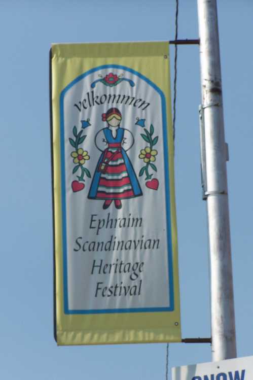 A colorful banner reading "Velkommen" for the Ephraim Scandinavian Heritage Festival, featuring a traditional figure.