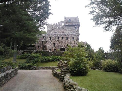 A stone castle surrounded by greenery, with a winding path leading up to it under a cloudy sky.
