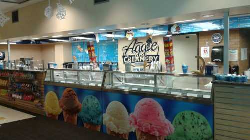 A colorful ice cream shop counter with various flavors displayed in tubs and a vibrant mural of ice cream cones.