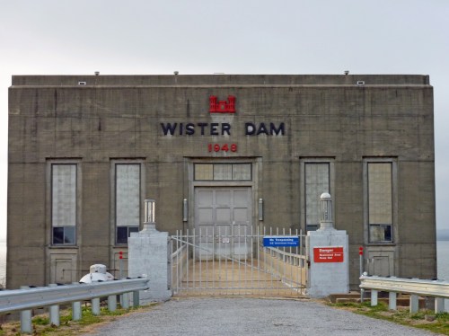 Front view of Wister Dam, a concrete structure with a gate, built in 1948, surrounded by a cloudy sky.