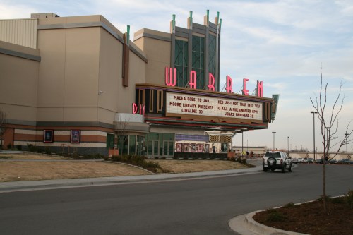 Exterior of the Warren Theater with a marquee displaying movie titles and a parking lot in front.