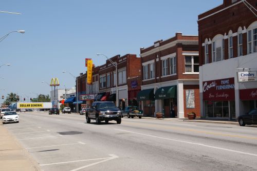 A street view featuring shops, a McDonald's, and a Dollar General, with cars parked and driving along the road.