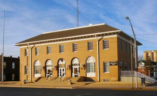 Historic brick building with large arched windows and a staircase, set against a clear blue sky.