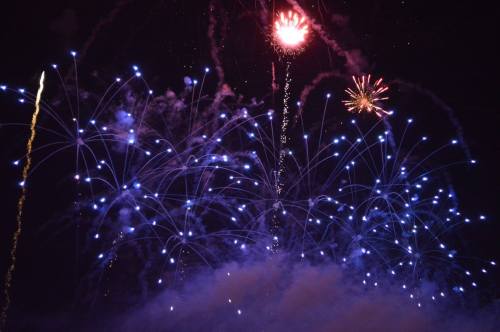 Colorful fireworks burst in the night sky, creating a vibrant display of lights and patterns against a dark backdrop.