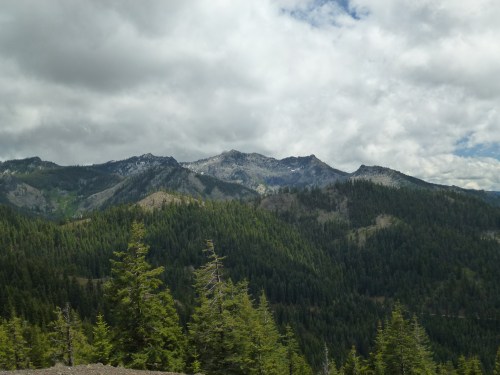 A scenic view of mountains covered in greenery under a cloudy sky.