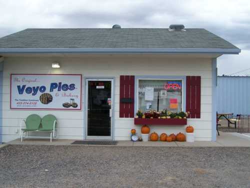 A small bakery with a sign reading "Veyo Pies & Bakery," featuring pumpkins and an open sign in the window.