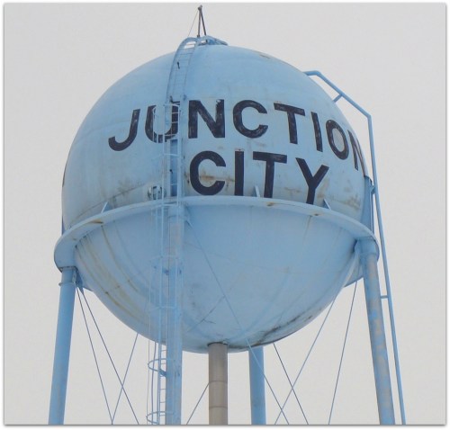 A blue water tower with the words "Junction City" prominently displayed on its spherical tank.