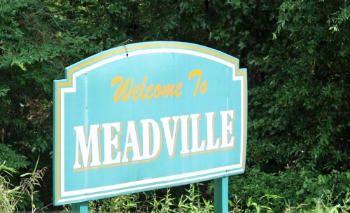 A welcome sign for Meadville surrounded by greenery.