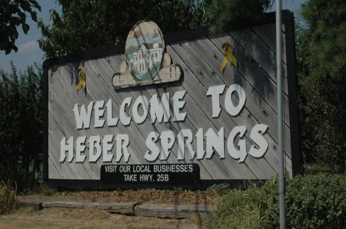 Welcome sign for Heber Springs, featuring a decorative design and information about local businesses and highway access.