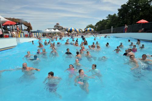 A crowded water park wave pool with people swimming and enjoying the water on a sunny day.