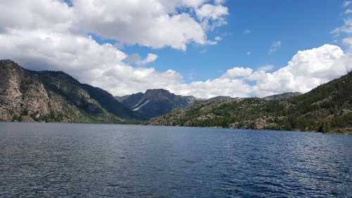 A serene lake surrounded by mountains under a partly cloudy sky.