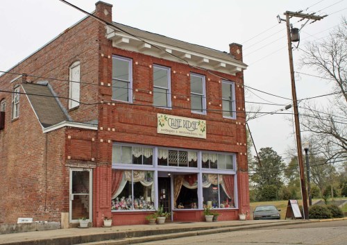 A brick building with large windows, featuring a sign that reads "Cane Ridge" and decorative curtains inside.