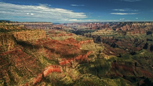 A panoramic view of the Grand Canyon, showcasing layered rock formations and vibrant colors under a clear blue sky.