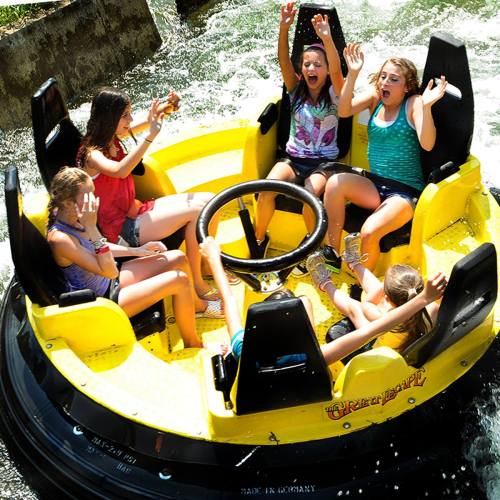 A group of excited children enjoying a spinning water ride, splashing and laughing in a bright yellow boat.