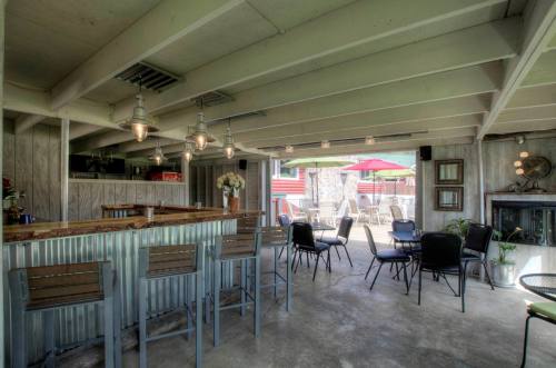 A spacious indoor bar area with metal stools, tables, and an open view to an outdoor patio with umbrellas.