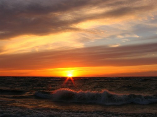 A vibrant sunset over the ocean, with waves gently crashing against the shore and colorful clouds in the sky.