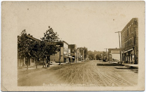Historic photo of Main Street in Clermont, Iowa, featuring dirt roads and early 20th-century storefronts.