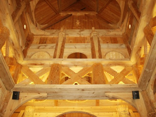 Interior view of a wooden structure, showcasing beams, columns, and a warm, rustic design.