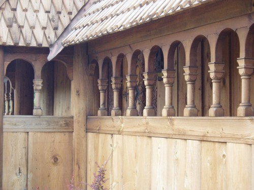 Wooden structure featuring decorative arches and columns, showcasing intricate craftsmanship and natural materials.