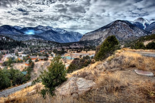 A scenic view of mountains and a valley with a small town, under a cloudy sky.