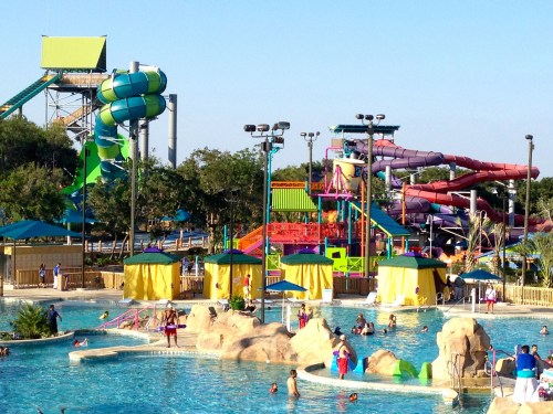 A vibrant water park featuring colorful slides, pools, and families enjoying the sunny day.