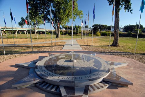 A stone compass rose at a park, surrounded by flags, marking the geographic center of the contiguous United States.