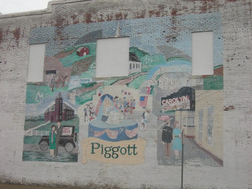 A colorful mural depicting a town scene with people, buildings, and the name "Piggott" prominently displayed.