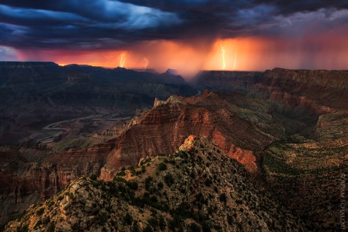 Dramatic landscape of a canyon under a stormy sky, with lightning illuminating the dark clouds and rugged terrain.