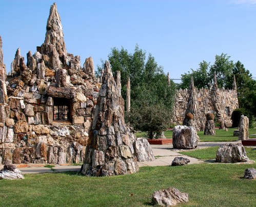 A unique stone structure with spiky rock formations and grassy areas under a clear blue sky.