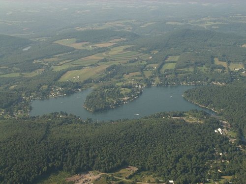 Aerial view of a lush green landscape featuring a winding lake surrounded by fields and forests.