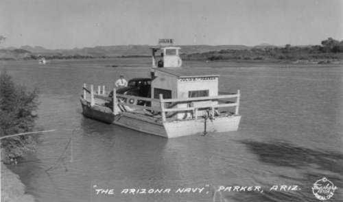 A vintage ferry named "The Arizona Navy" transporting a car across a river in Parker, Arizona.