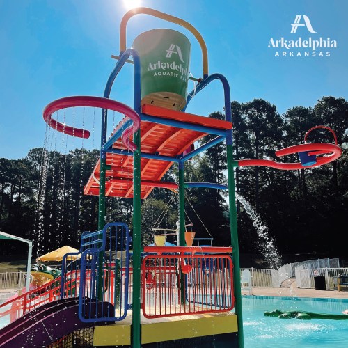 Colorful water play structure at Arkadelphia Aquatic Park, featuring slides and water features against a sunny backdrop.
