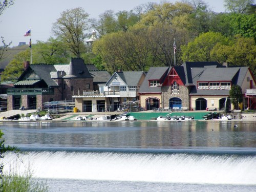 Scenic view of colorful buildings along a river, with boats docked and a waterfall in the foreground.
