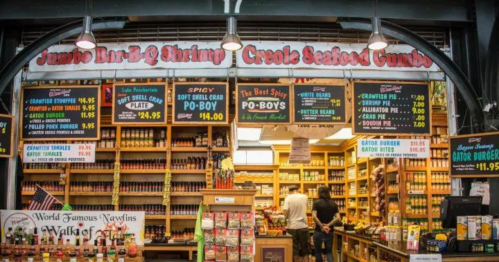 A vibrant seafood market display featuring menu boards for shrimp, gumbo, and other dishes in a bustling setting.