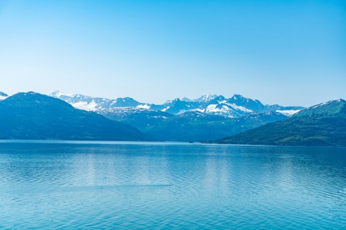 A serene lake surrounded by snow-capped mountains under a clear blue sky.