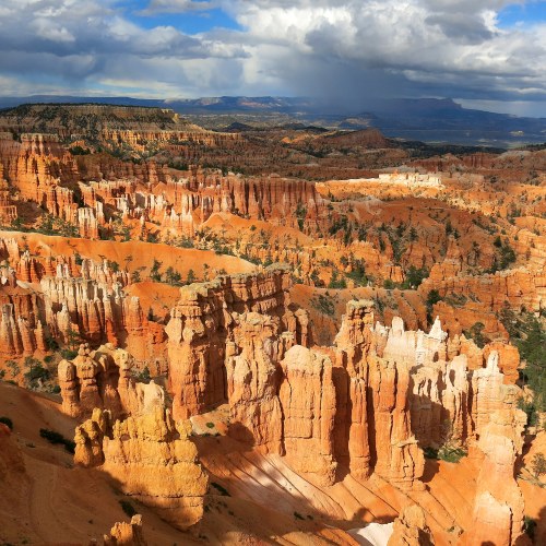 A panoramic view of Bryce Canyon's colorful rock formations and hoodoos under a partly cloudy sky.