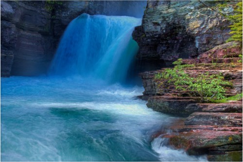 A serene waterfall cascades over rocky cliffs into a turquoise pool, surrounded by lush greenery.