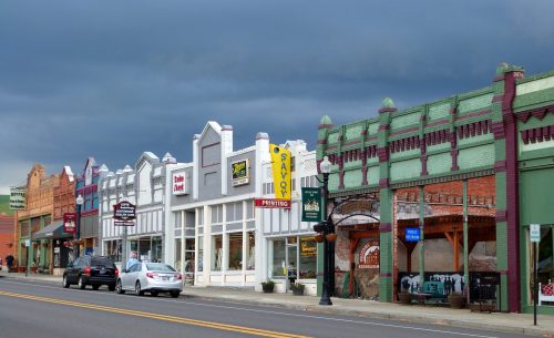A row of colorful historic buildings with shops, under a cloudy sky, along a street.