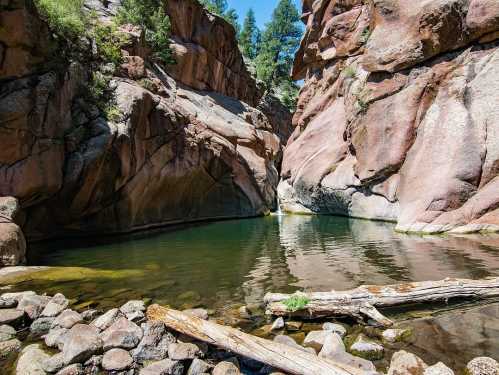 A serene natural landscape featuring a calm pool surrounded by towering rock formations and lush greenery.