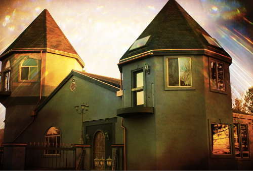 A unique two-towered house with a colorful exterior and large windows, set against a dramatic sky.